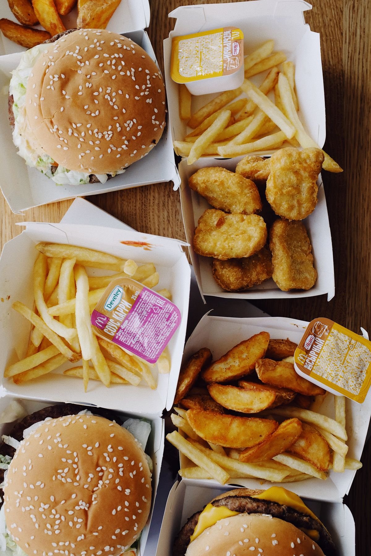 Burgers and french fries photographed from above on a wooden board, used as an editorial illustration for “A global burger price comparison without false precision”