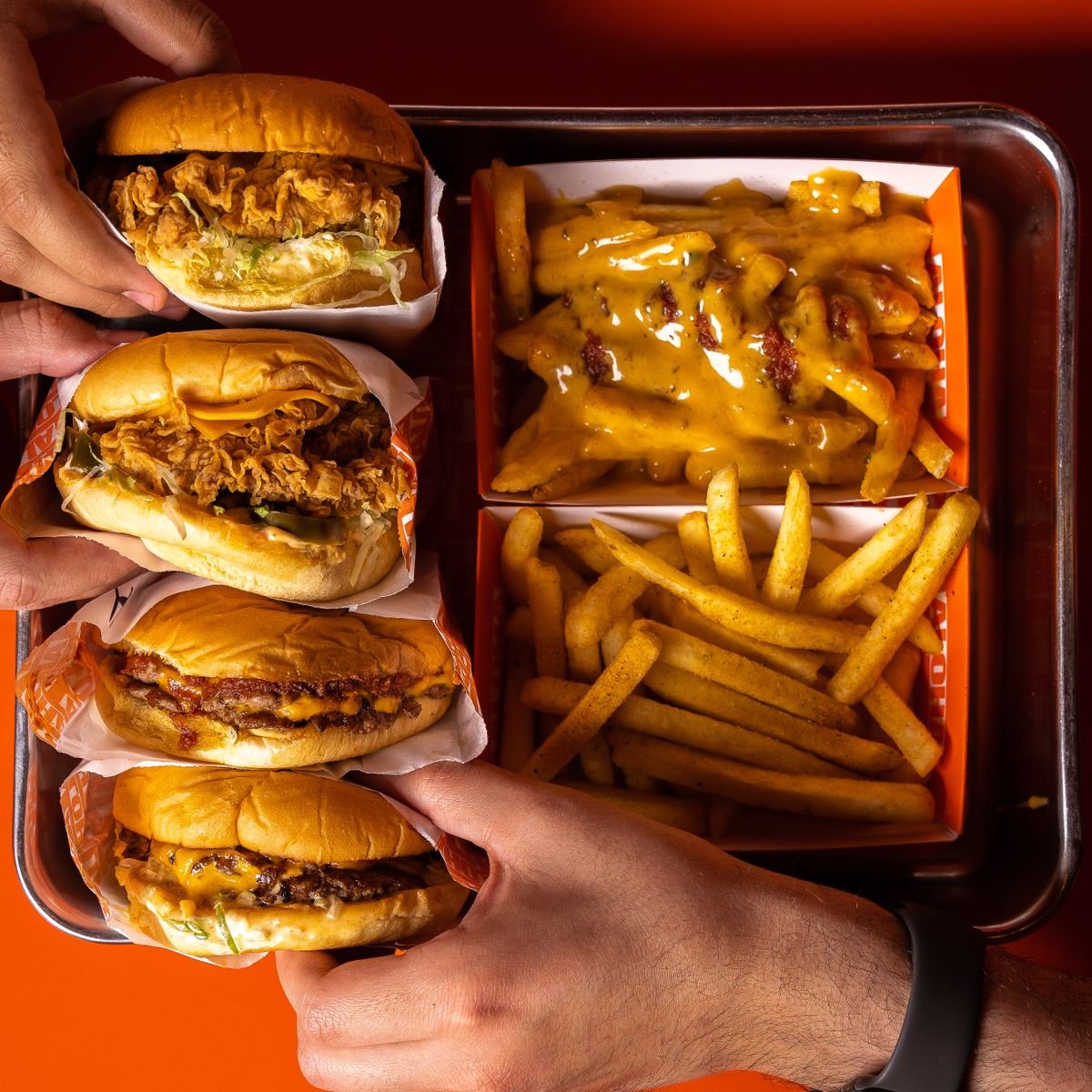 A tray of burgers, cheesy fries and sides seen from above