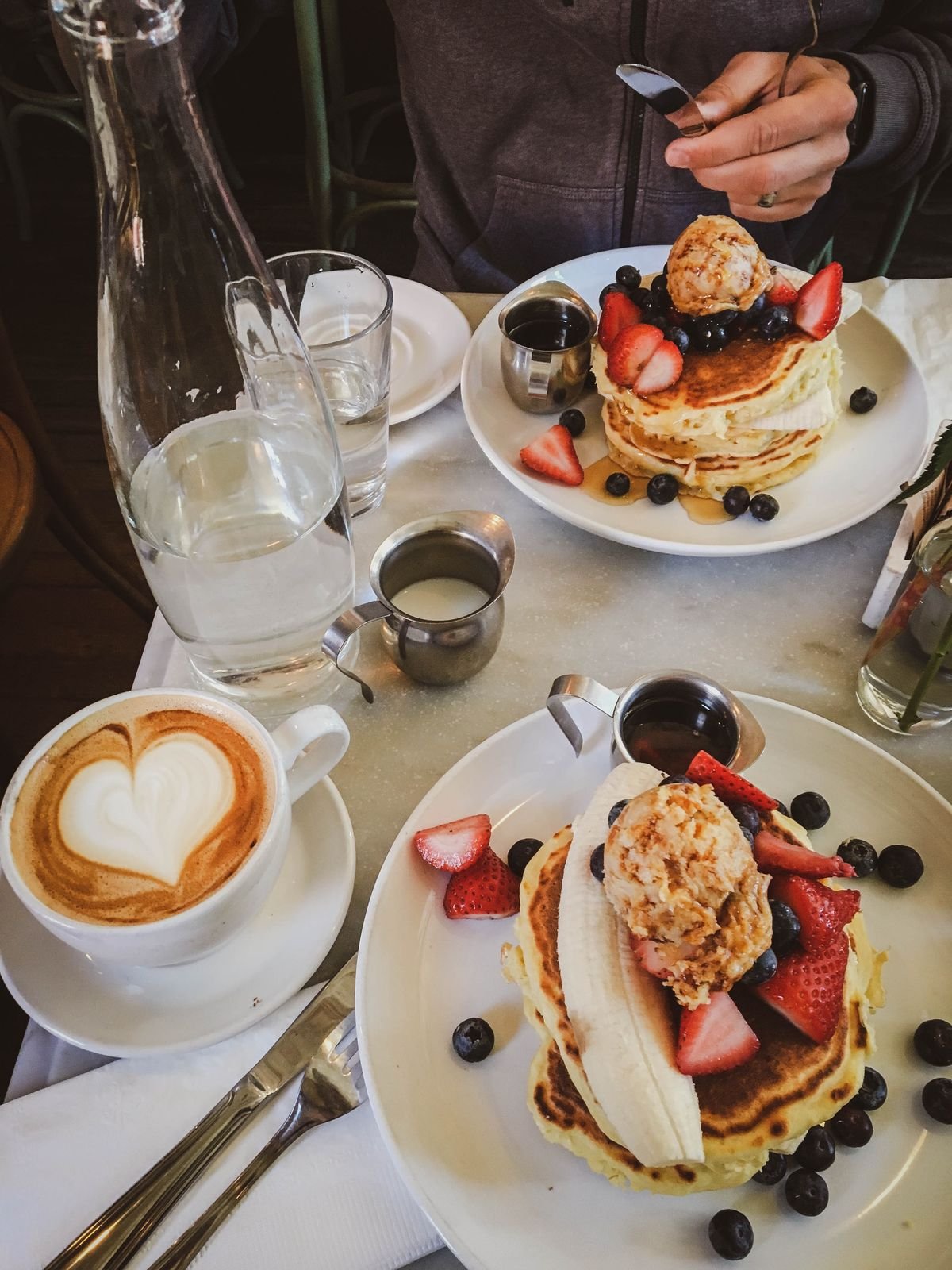 Pancakes with fruit, a cappuccino and vanilla ice cream at breakfast