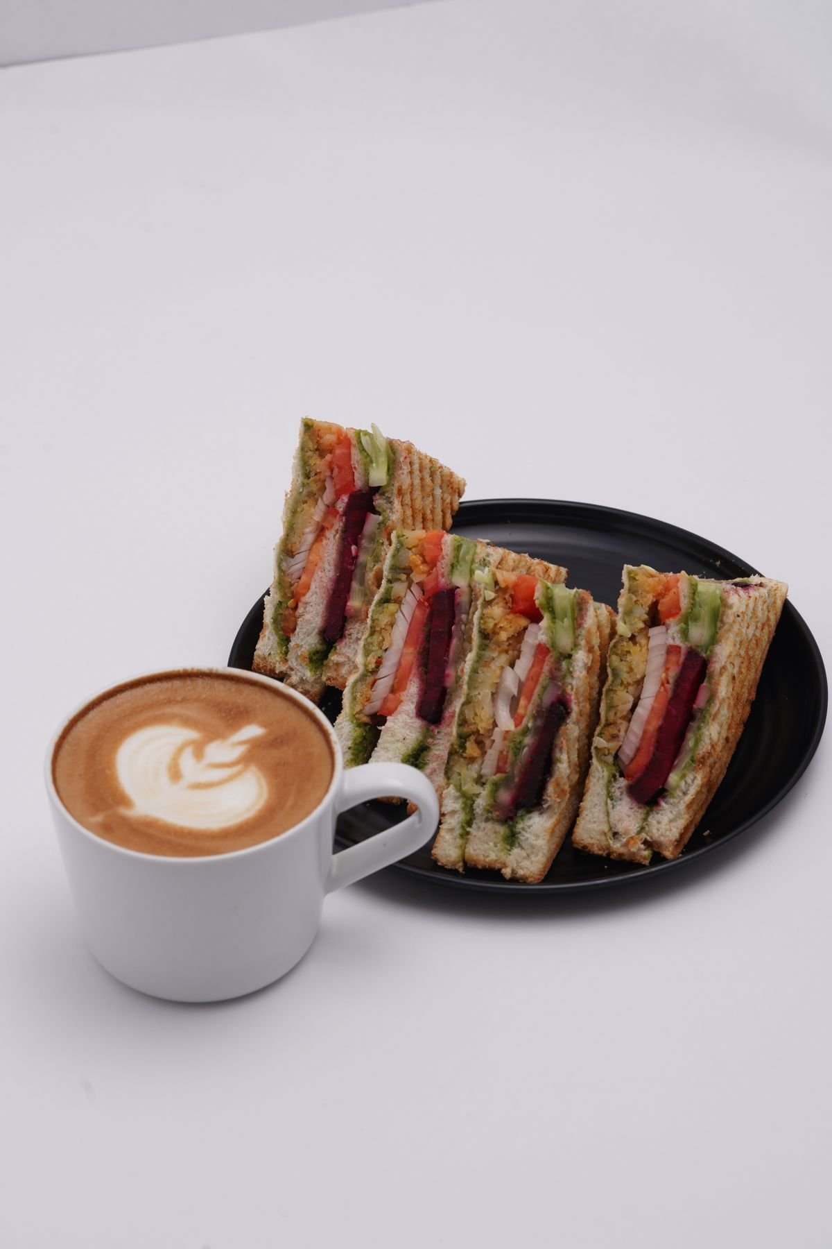 A sandwich platter with a creamy latte, used as an editorial illustration for “Fast-food road trips: menus as travel souvenirs”